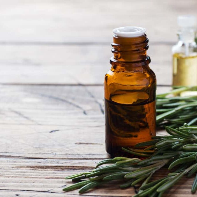Rosemary essential oil in a glass bottle with fresh branch rosemary herb on wooden table for spa,aromatherapy and bodycare.Copy space